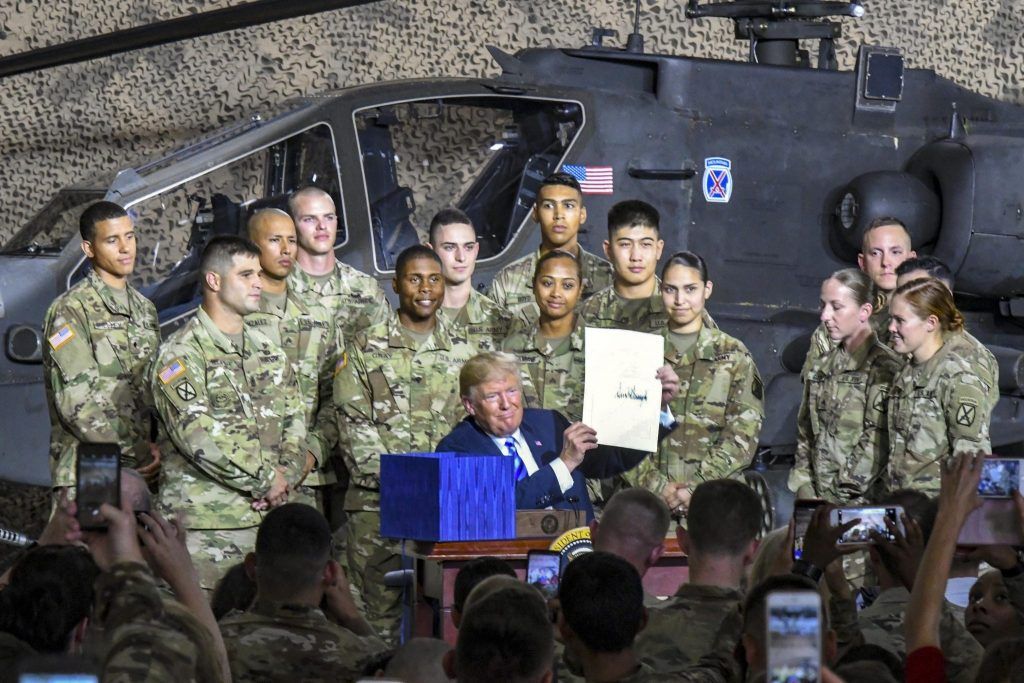 President Donald Trump poses with service members after signing the National Defense Authorization Act for Fiscal Year 2019 during a visit to Fort Drum, New York, on August 13, 2018.