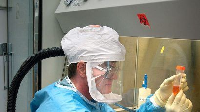 A CDC staff microbiologist examines reconstructed 1918 Pandemic Influenza Virus contained at a Biosafety Level 3-enhanced lab. Photo credit: Photo Credit: James Gathany/CDC