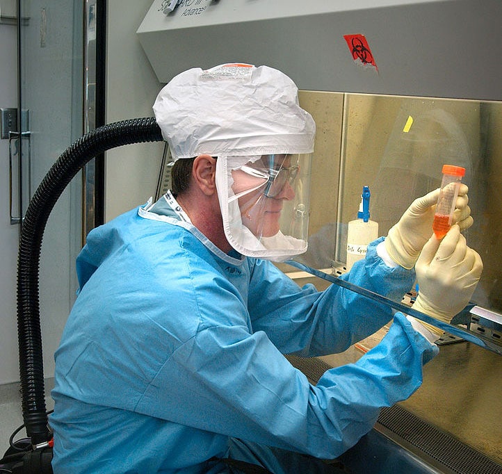 A CDC staff microbiologist examines reconstructed 1918 Pandemic Influenza Virus contained at a Biosafety Level 3-enhanced lab. Photo credit: Photo Credit: James Gathany/CDC