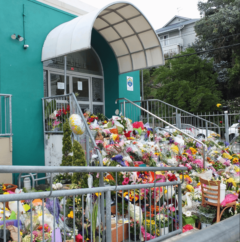 Flowers outside a mosque in New Zealand to commemorate the victims of an attack on two mosques that killed 50 people. Credit: Mike Dickison via Wikimedia Commons. CC BY 4.0. (Edited)