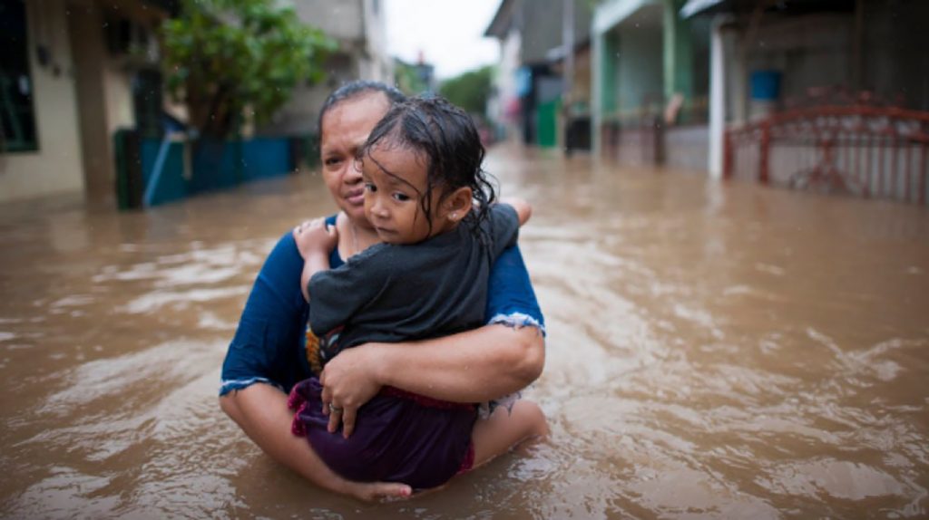 mother and child up to waist in floodwaters