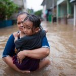 mother and child up to waist in floodwaters