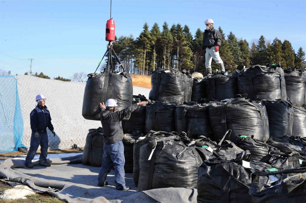 Workers stacking bags of soil.