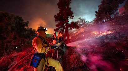 Firefighters work near the Getty Center in Los Angeles on October 28. Thousands of residents were forced to evacuate their homes after a fast-moving wildfire erupted.
