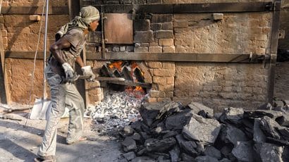 man shoving coal into oven in India