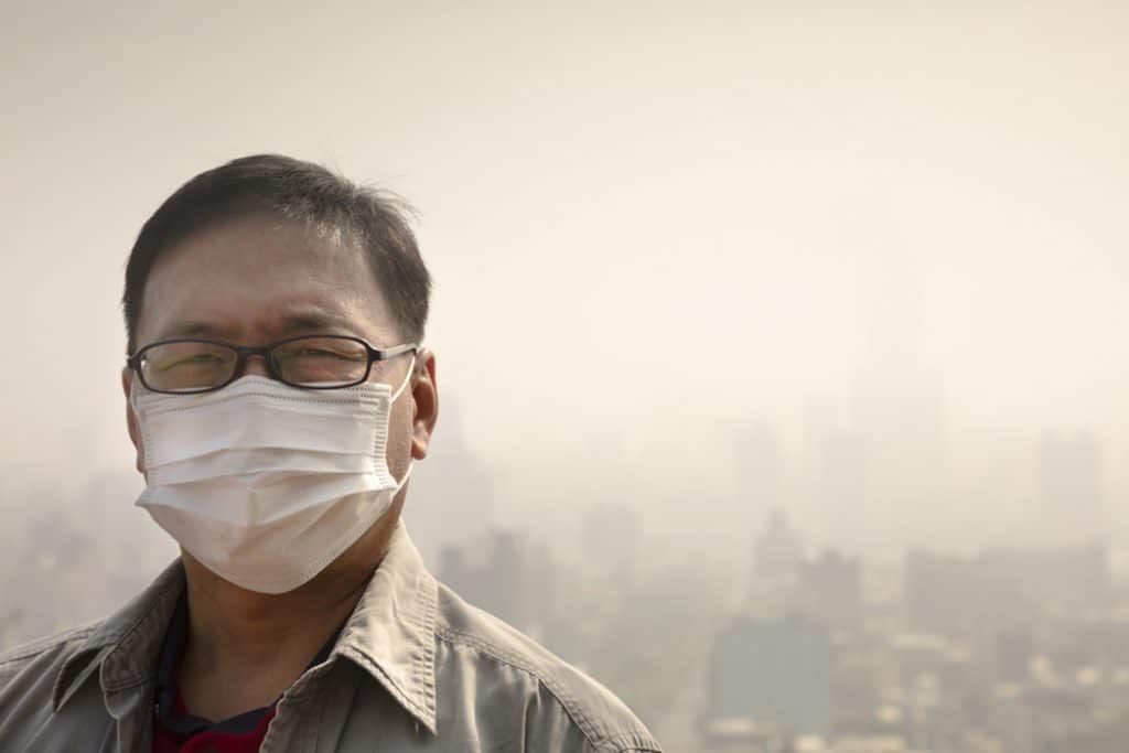 Man with face mask against hazy cityscape