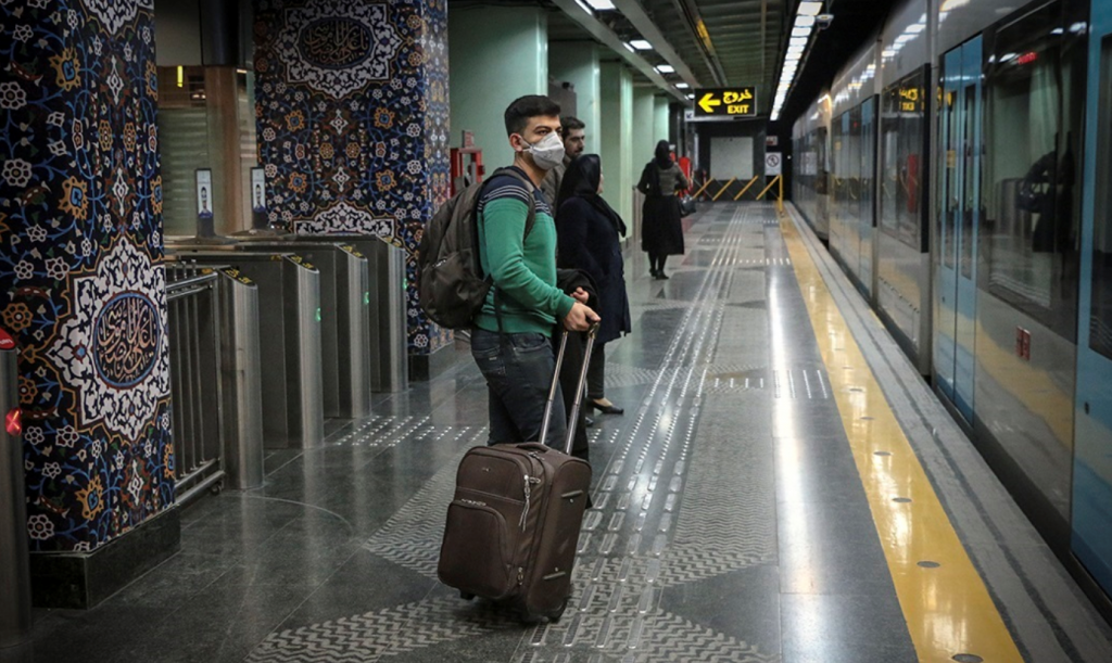 Passengers wait for the train with masks on.