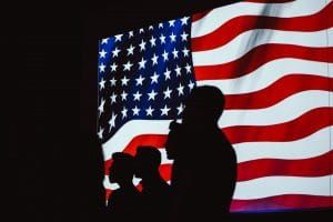 silhouettes of people in front of US flag