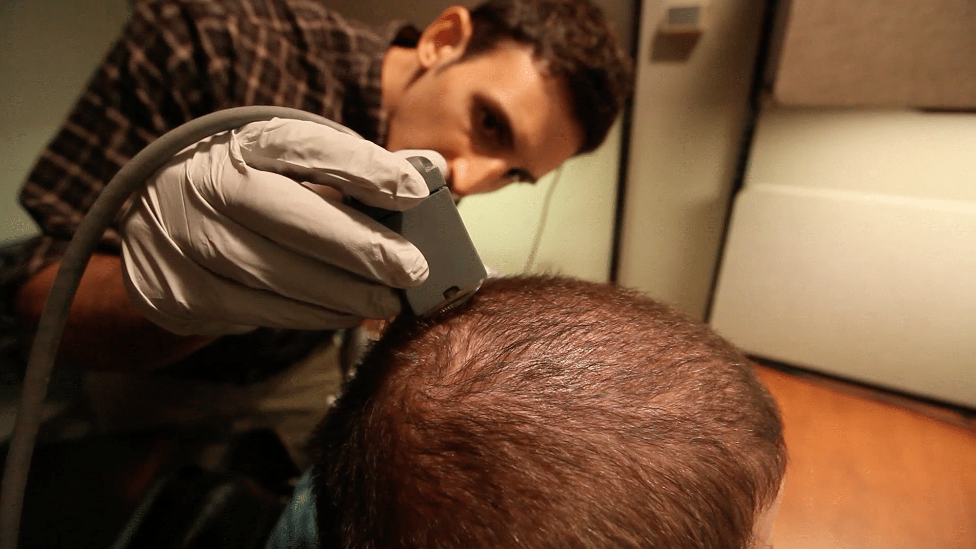 Battelle engineer Nicholas Annetta adjusts a cable attached to the Utah microelectrode array inserted in Ian Burkhart's brain. (<a href="http://osuwmc.multimedia-newsroom.com/index.php/2016/04/13/man-uses-his-own-brainwaves-to-retrain-his-paralyzed-hand/">The Ohio State University Wexner Medical Center</a>)