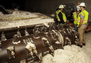 Ed Garza, assistant manager for the Energy Department's Carlsbad Field Office, explains WIPP’s continuous mining machine to Thomas Mooney and Jaffet Ferrer-Torres of the department's Office of Environmental Management during a July 2020 underground tour. Energy Department photo.