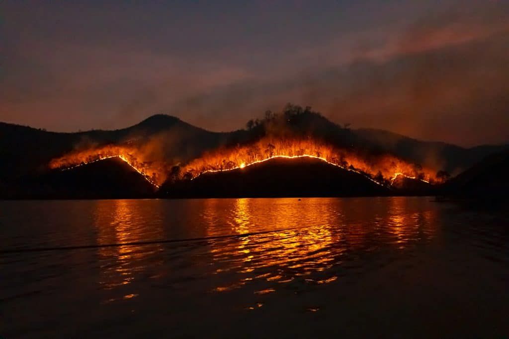 wildfire on mountain reflected in lake