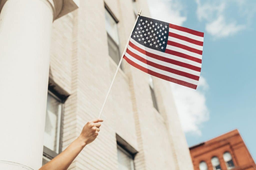 Hand waving American flag. Credit: Paul Weaver (@paulweaver). Image accessed via Unsplash. Unsplash License.
