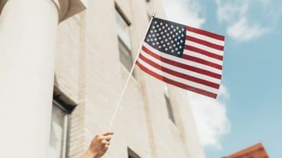 Hand waving American flag. Credit: Paul Weaver (@paulweaver). Image accessed via Unsplash. Unsplash License.
