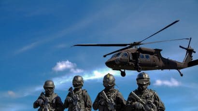 Four soldiers carrying rifles near helicopter under blue sky. Credit: Somchai Kongkamsri. Access via Pexels. Free to use.