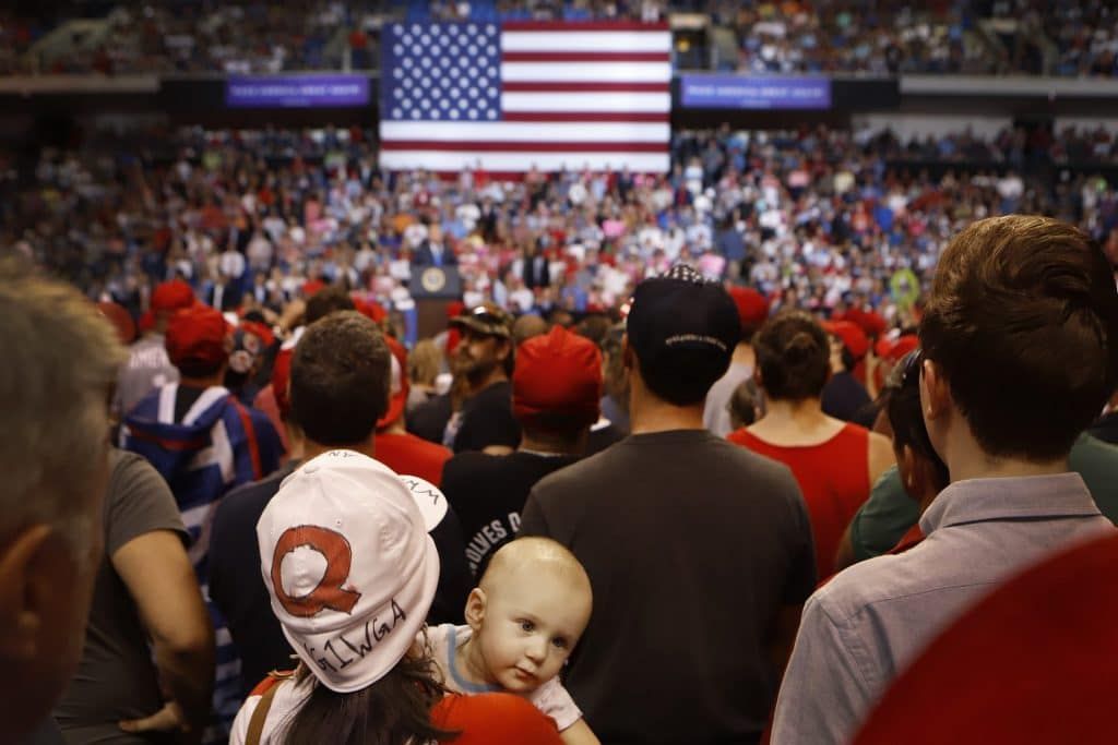 A woman wearing a "Q" hat with her son listens to President Trump speak to a large crowd in 2018 in Wilkes Barre, Penn. (Photo by Rick Loomis/Getty Images)