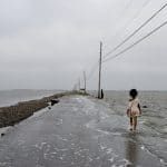 school child walking down flooded road in Gulf of Mexico