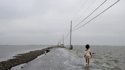 school child walking down flooded road in Gulf of Mexico