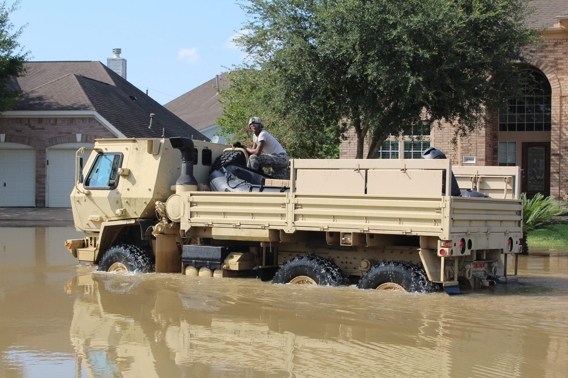 A US Army soldier atop a military vehicle in a street flooded by Hurricane Harvey