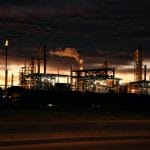 oil refinery billowing smoke at sunset