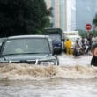 drivers and bikers make their way through flooded streets in Hanoi, Vietnam