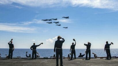 silhouettes of sailors waving at India plane fly-by