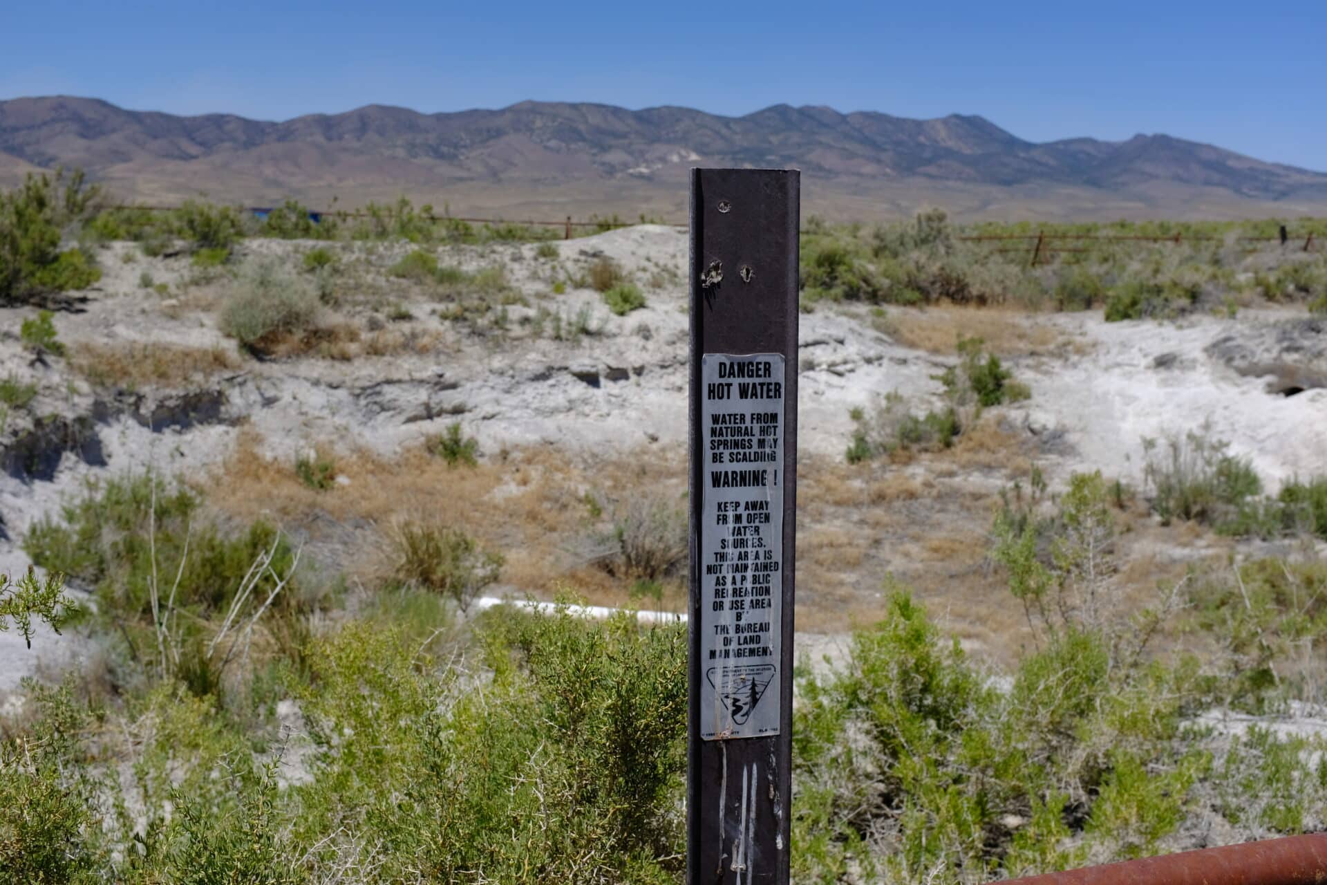 A warning sign at the Jersey Valley hot spring, which once filled at a rate of 35 to 75 gallons per minute, filling the basin and spilling over into the valley below. (Jessica McKenzie)