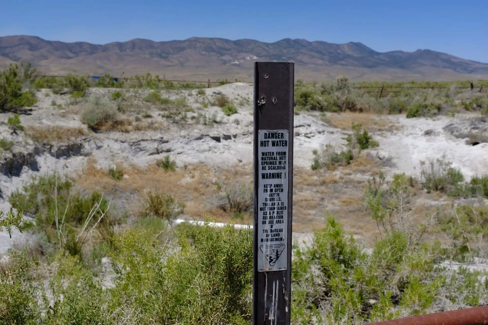 A warning sign at the Jersey Valley hot spring, which once filled at a rate of 35 to 75 gallons per minute, filling the basin and spilling over into the valley below. (Jessica McKenzie)