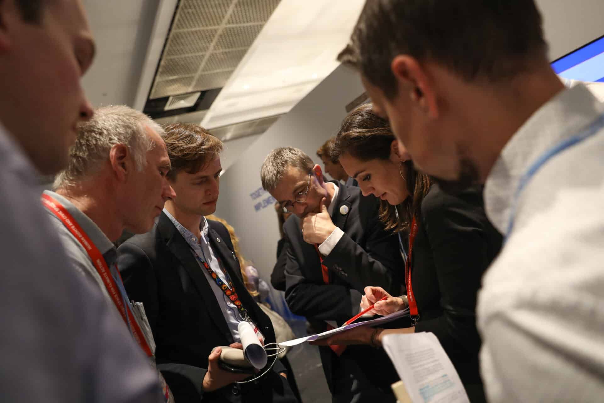 delegates in conversation over a clipboard