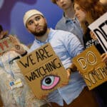 climate activists at cop27 holding signs that read we are watching and do something