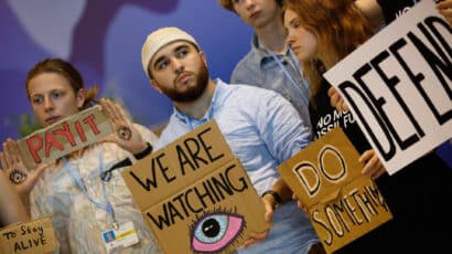 climate activists at cop27 holding signs that read we are watching and do something