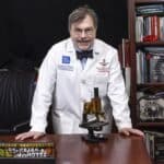 Peter Hotez at his desk in a white physician coat
