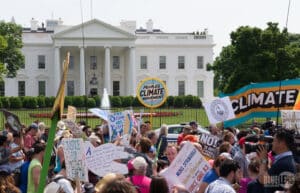a climate protest outside the white house, people holding signs