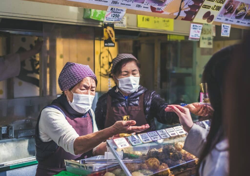 masked women working at a food stall