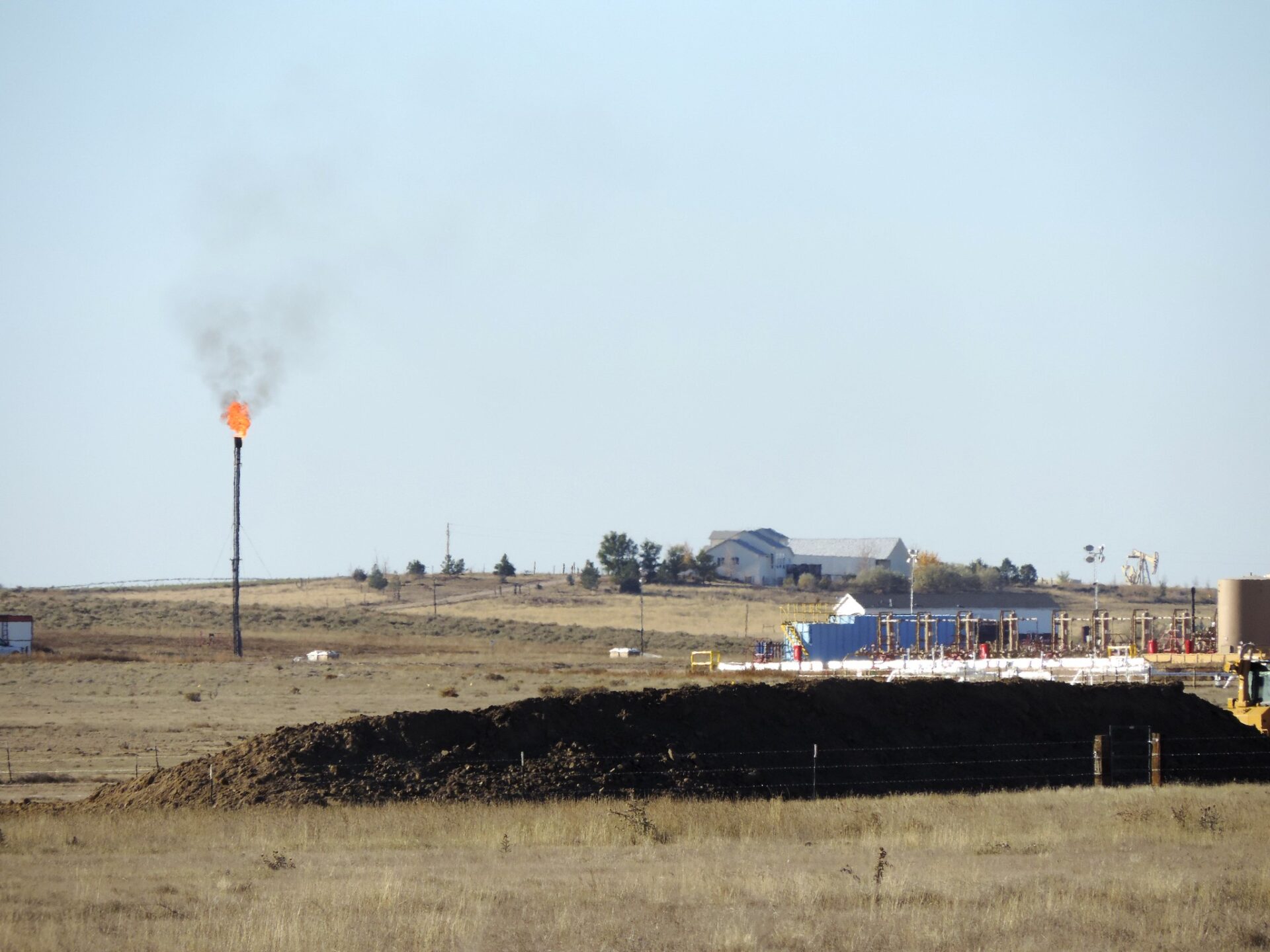 a smoking flare in rural colorado at a fracking site, near a home