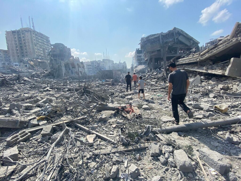 people walking through destruction in Gaza