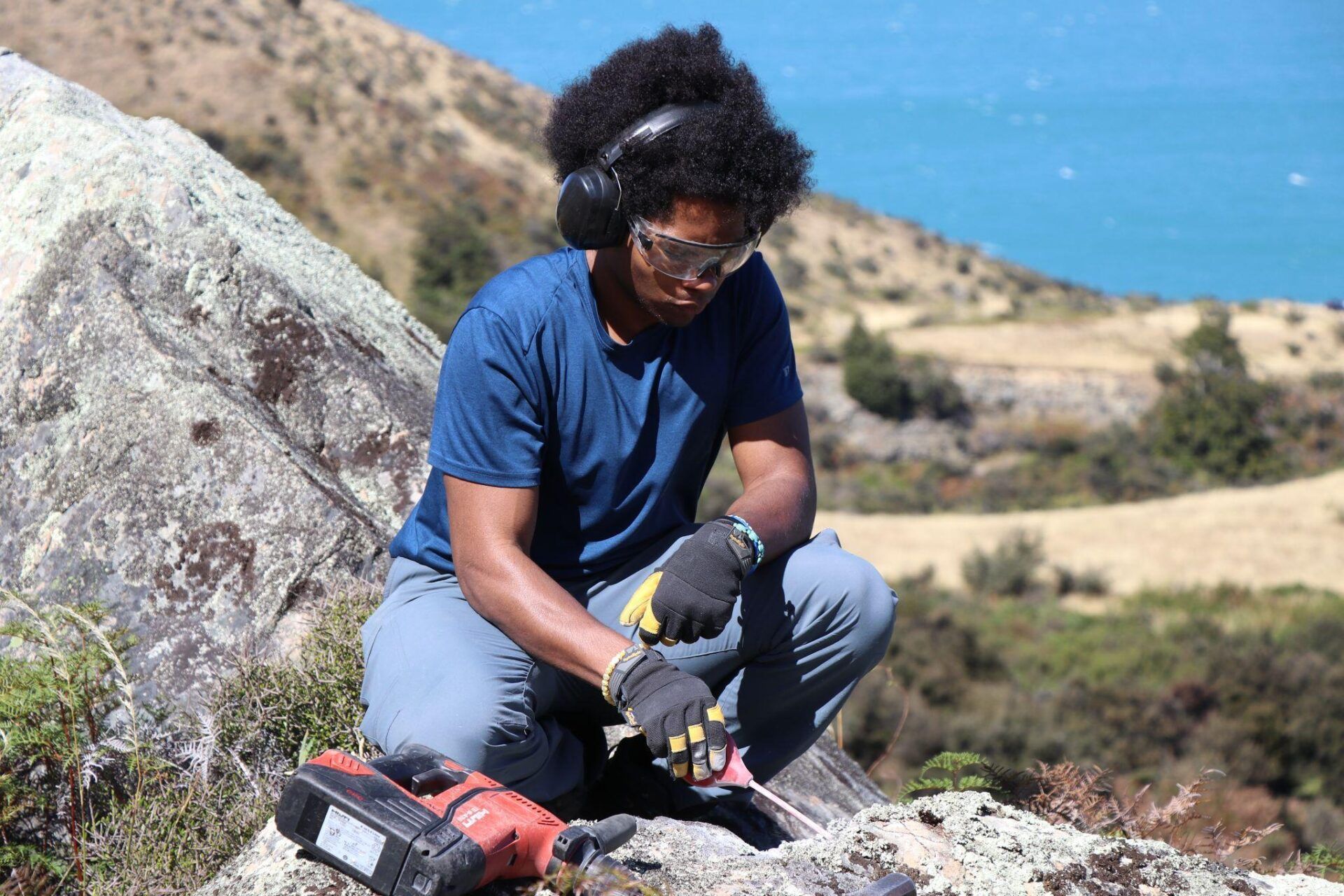 Alexzander Roman prepares to sample a boulder by first drilling a hole and clearing away debris. The ages that Roman and other researchers have gathered from boulders are evidence of the Last Glacial Period being a global event. (Louise Kim / Medill Reports)