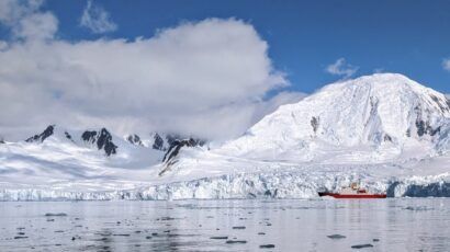 red research ship next to edge of Antarctic ice