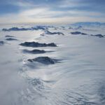 mountain peaks projecting up above a surface of inland ice and snow in West Antarctica