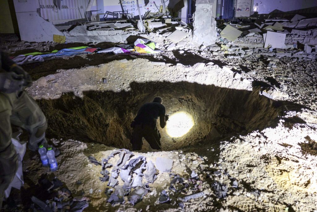 Members of Israel's Home Front Command and police forces inspect a crater left by an exploded projectile at a heavily-damaged school building in Israel's southern city of Gedera on October 1, 2024, after Iran launched a barrage of missiles at Israel in response to the killings of Lebanese Hezbollah leader Nasrallah and other Iran-backed militants. Reports said Iran fired between 150 and 200 missiles in the attack, the country's second on Israel after a missile and drone attack in April in response to a deadly Israeli air strike on the Iranian consulate in Damascus. (Photo by MENAHEM KAHANA/AFP via Getty Images)