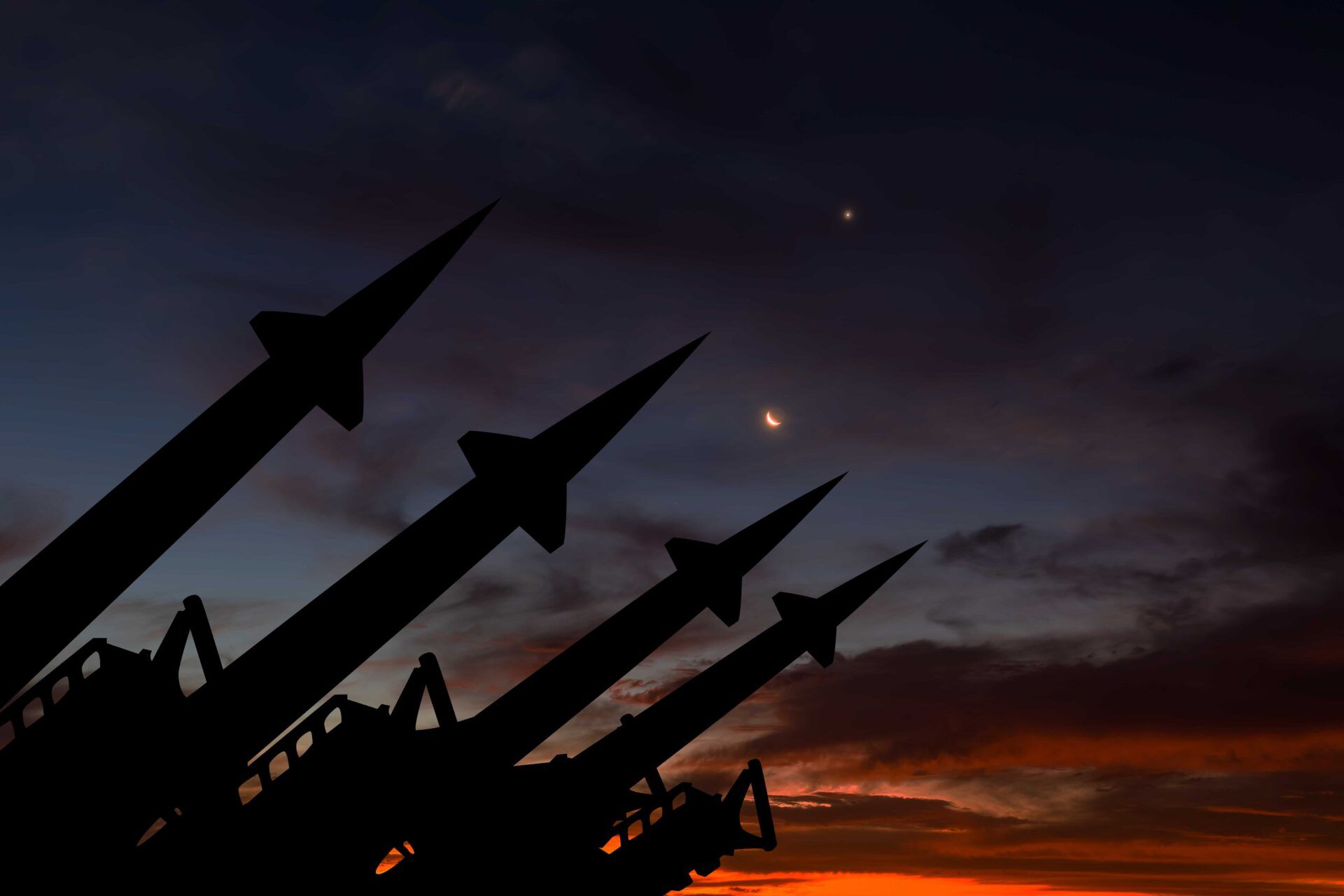 The silhouette of missiles with a sunset behind them.