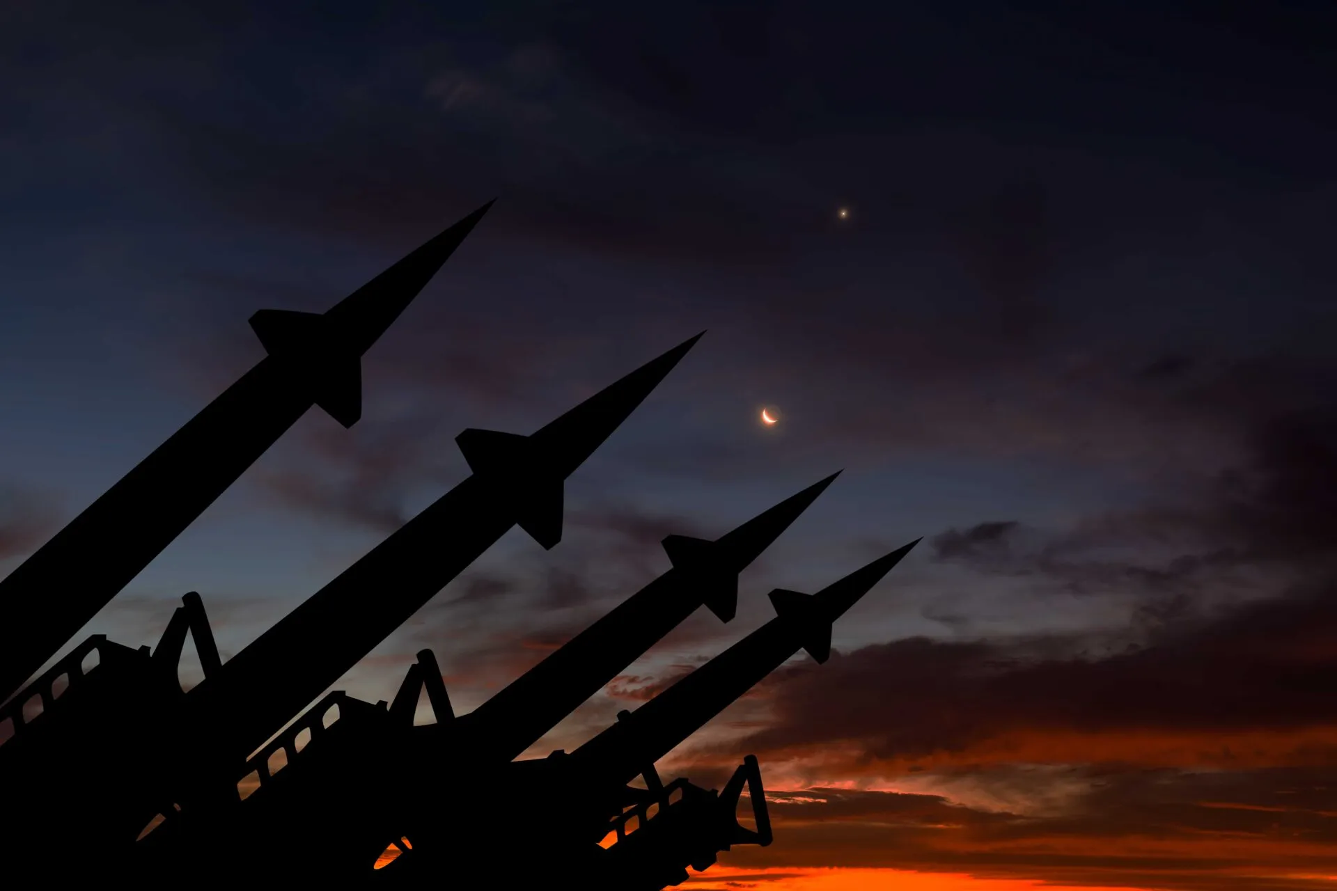 The silhouette of missiles with a sunset behind them.