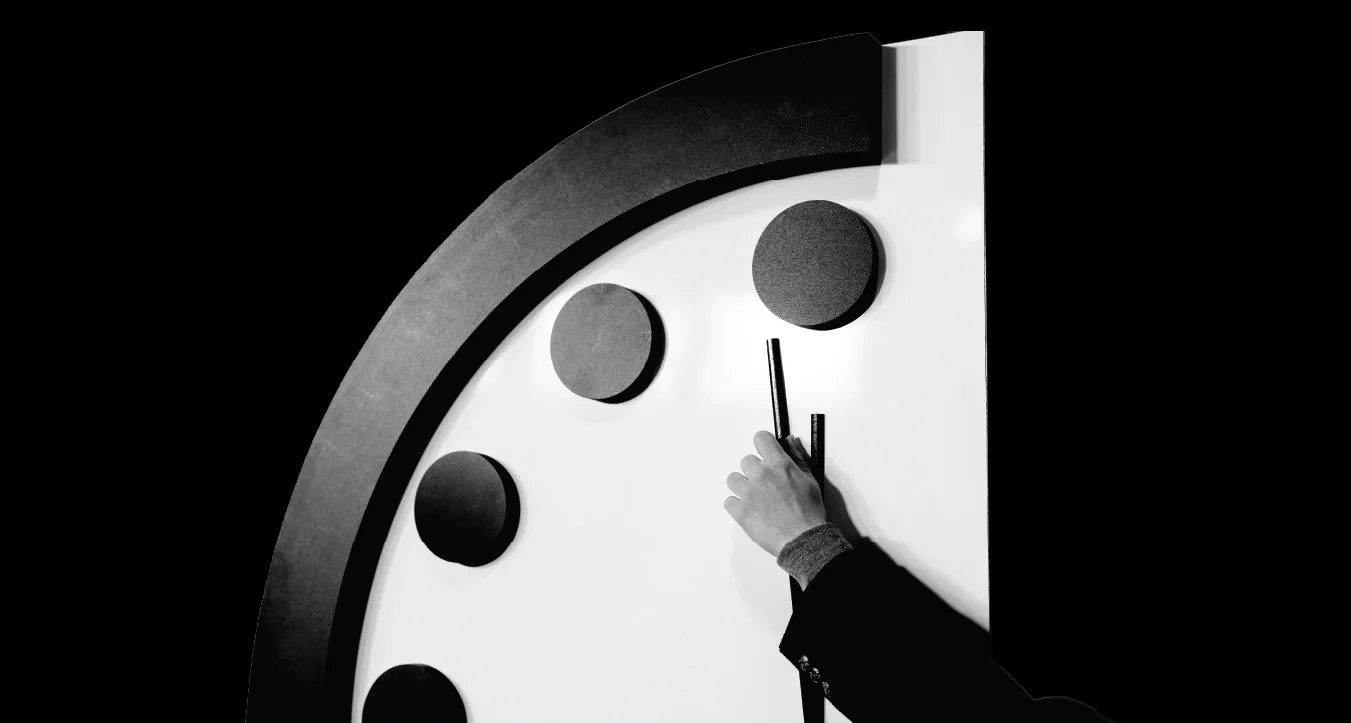 A person holds the minute hand of the Doomsday Clock at the 2024 Clock announcement.