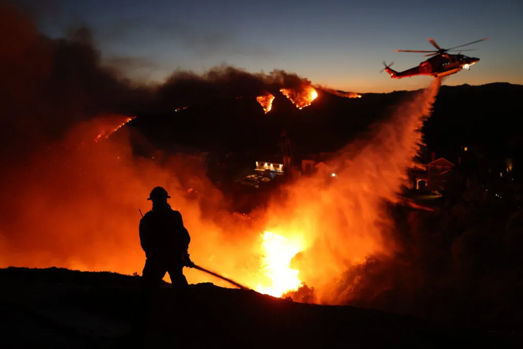 firefighter in silhouette with multiple fires in background