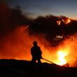 firefighter in silhouette with multiple fires in background