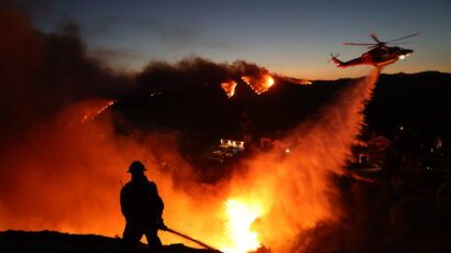 firefighter in silhouette with multiple fires in background