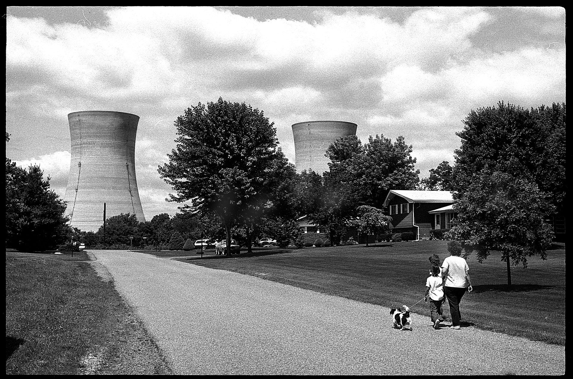 In Robert Del Tredici’s "Yellow Brick Road," a woman and two children walk a dog just down the road from Three Mile Island, mere weeks after the plant’s March 28, 1979, partial reactor meltdown. Courtesy Robert Del Tredici