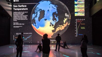 People looking at a large projection of the Earth showing a map of sea surface temperatures