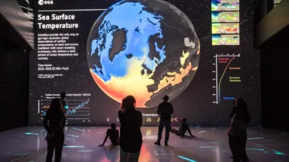 People looking at a large projection of the Earth showing a map of sea surface temperatures