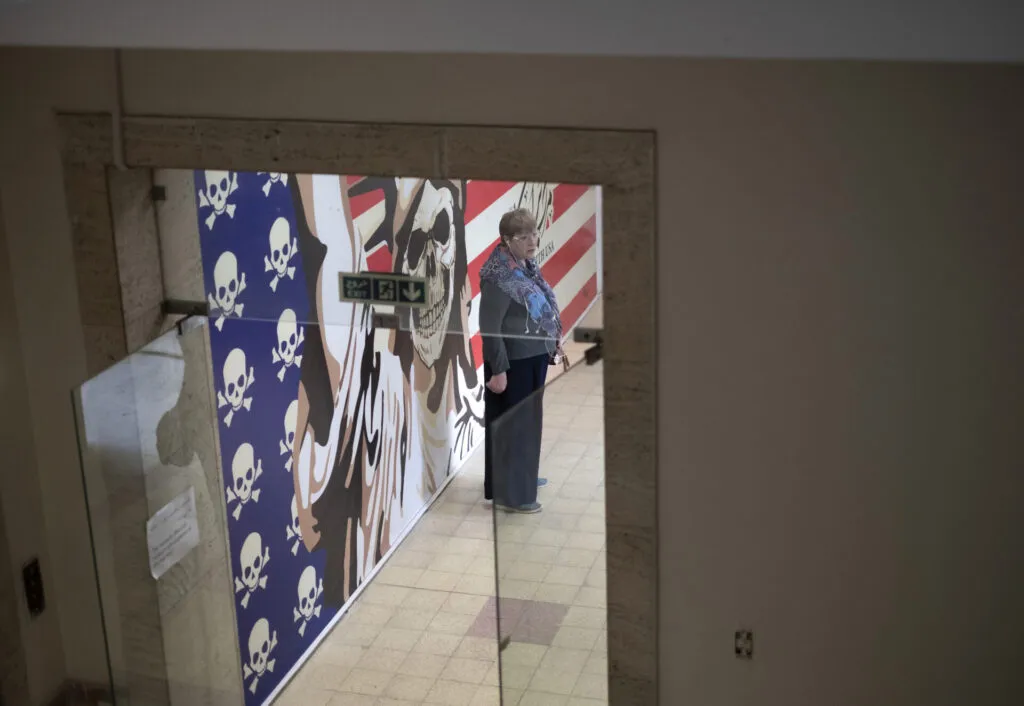 A Russian tourist stands in front of an anti-U.S. mural as she visits the former U.S. embassy in downtown Tehran, Iran, on April 12—the day of the Iran-U.S. nuclear discussions. (Photo by Morteza Nikoubazl/NurPhoto via Getty Images)