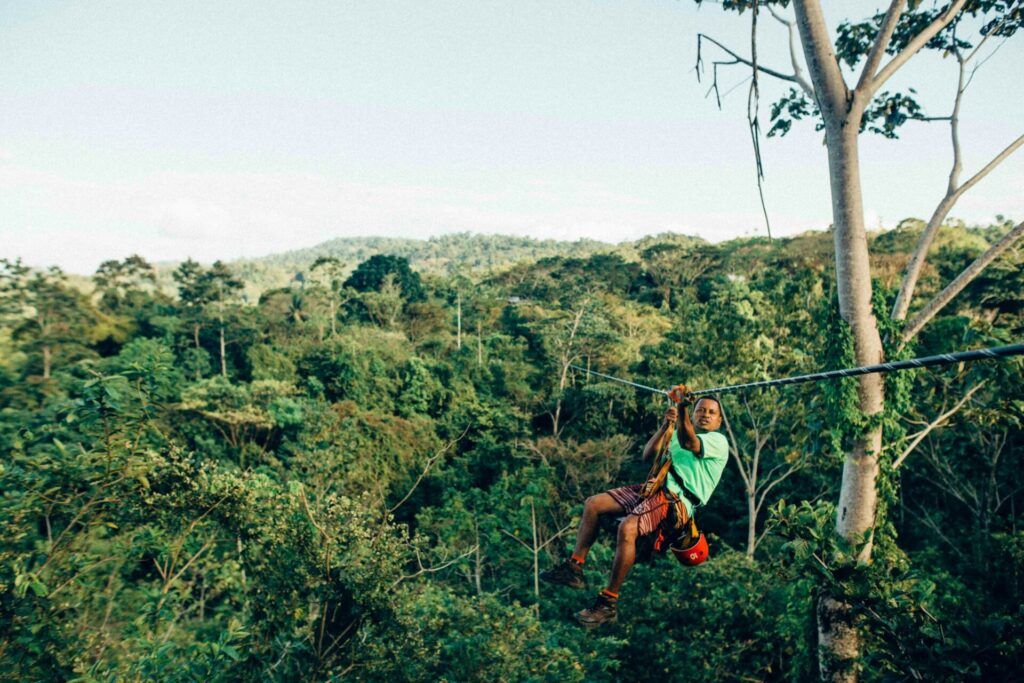 man on zipline in front of jungle